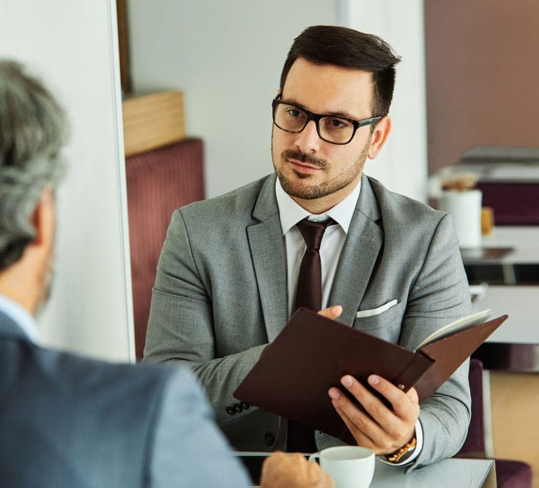 Businessman in a gray suit consulting with a patient in an office setting.