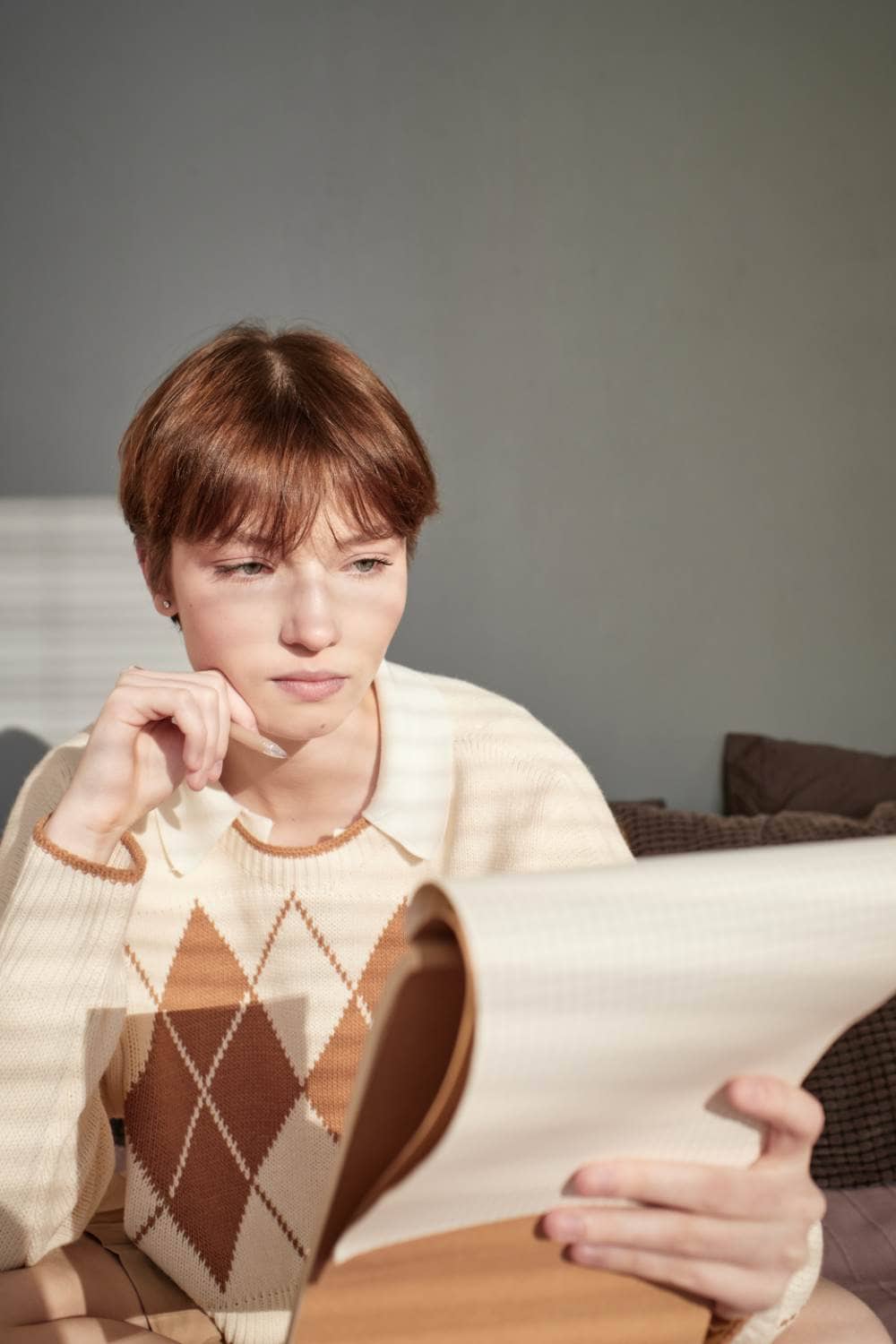 Woman reading a document with a thoughtful expression at home.
